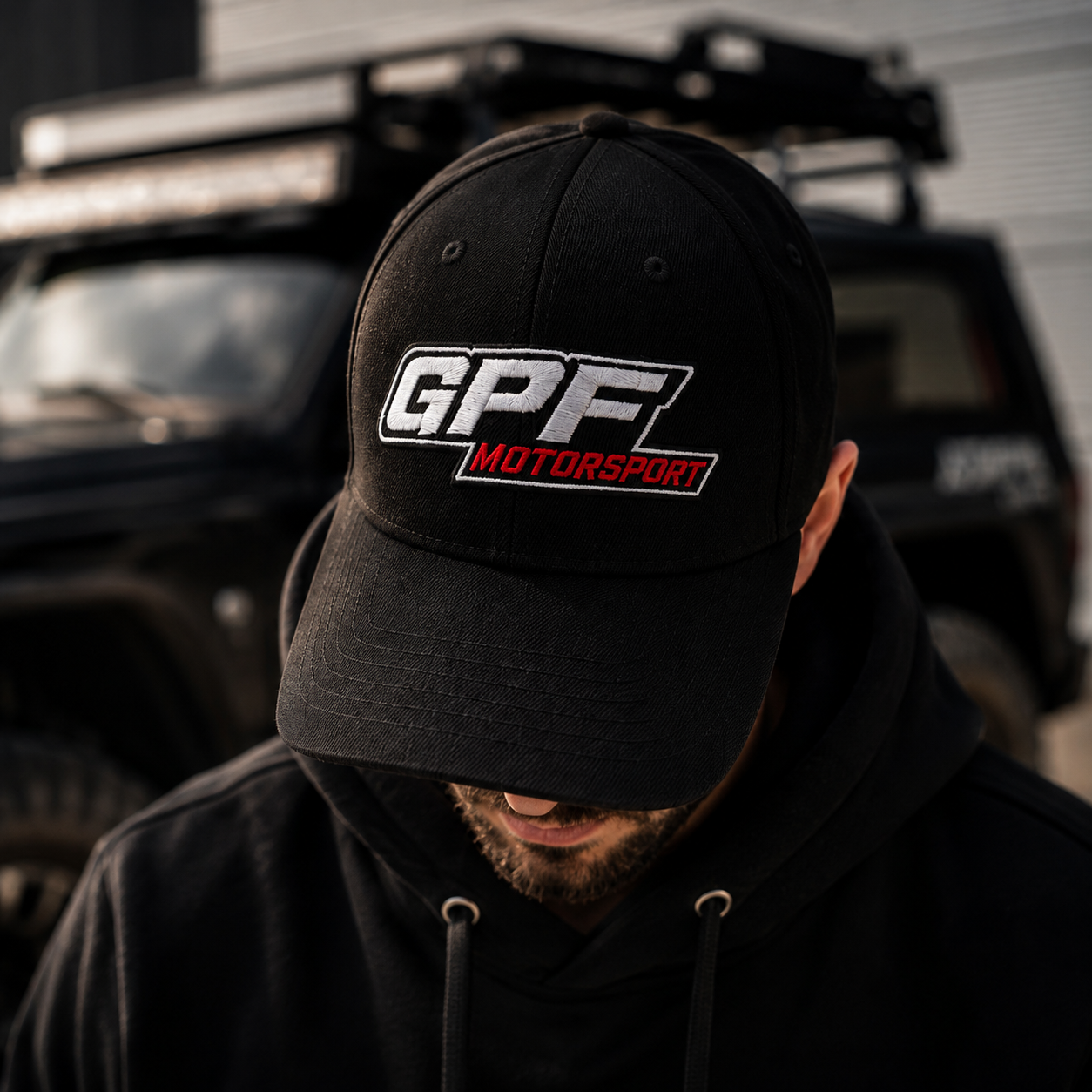 Casquette GPF-Motorsport portée devant un 4x4, logo brodé blanc et rouge sur le panneau avant